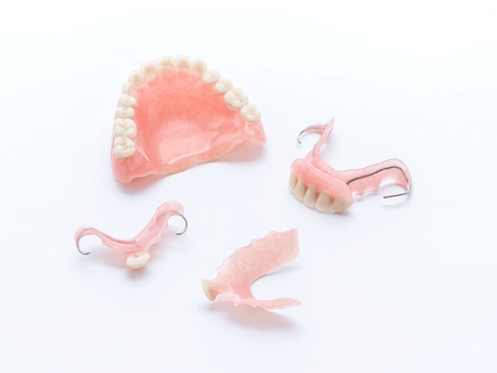 a pair of partial dentures next to a row of full dentures