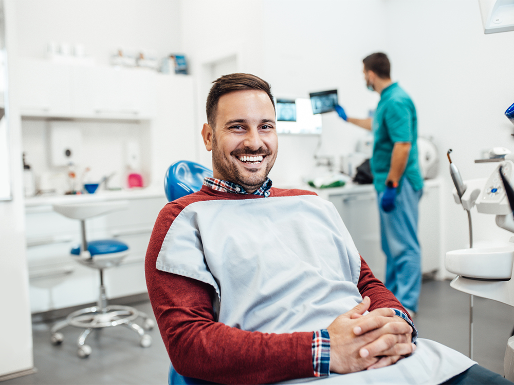 man sitting in dentist office smiling